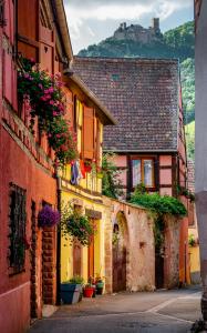 an alley in a town with a castle in the background at Ninichou in Ribeauvillé