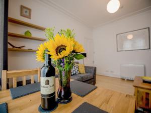 a bottle of wine and a vase of flowers on a table at Armadale Apartment in Fort William
