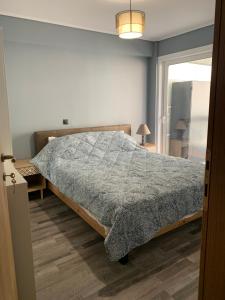 ein Schlafzimmer mit einem Bett mit einer grauen Bettdecke in der Unterkunft VARKIZA APARTMENT in Varkiza