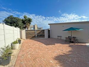 eine Terrasse mit einem Tisch und einem Sonnenschirm in der Unterkunft Jeffreysbay charming wooden house close to beach in Jeffreys Bay