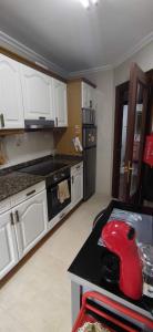 uma cozinha com armários brancos e um objecto vermelho num balcão em Apartamento en Solares em Valdecilla