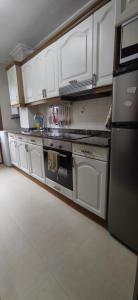 uma cozinha com armários brancos e um forno com placa de fogão em Apartamento en Solares em Valdecilla