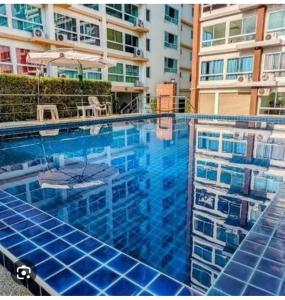 een groot blauw zwembad met een gebouw op de achtergrond bij Bangsaray Beach Resort in Bang Sare