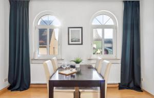 a dining room with a table and chairs and two windows at Awesome Apartment In Rtha With Kitchen in Rötha