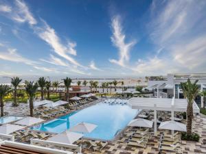 Draufsicht auf einen Resortpool mit Liegestühlen und Sonnenschirmen in der Unterkunft Rixos Gulf Hotel Doha in Doha