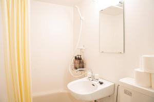 Un baño blanco con lavabo y espejo. en TasoneStayOsaka 心斎橋東周防町1st401, en Osaka