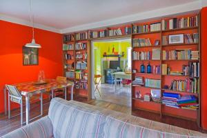 a living room with orange walls and a table and book shelves at Cottage a Bossolasco con piscina in Niella Belbo