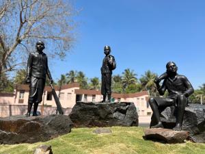 two statues of three men standing on rocks at Malgudi House - Commandant in Mysore