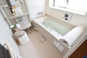 een witte badkamer met een bad en een raam bij OMOTENASHI in Kyoto +5 foto's