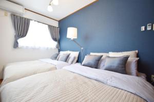 twee bedden in een slaapkamer met blauwe muren bij OMOTENASHI in Kyoto