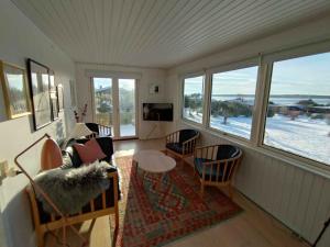 ein Wohnzimmer mit einem Sofa, Stühlen und Fenstern in der Unterkunft Cozy Summerhouse With Spectacular Views! in Ølsted