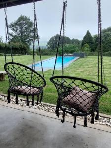 two chairs hanging from a porch with a pool at 9 Stoney Way House in Underberg