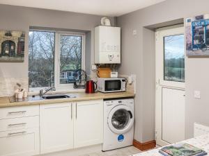 a kitchen with a washing machine and a microwave at Bryn Poeth in Bodorgan