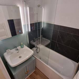 ein Badezimmer mit einem Waschbecken, einer Badewanne und einem Spiegel in der Unterkunft Le Montagnard in Mijoux