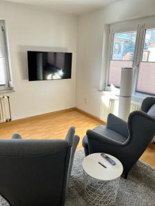 sala de estar con 2 sillas y TV de pantalla plana en Feel like Home 2, en Biberach an der Riß
