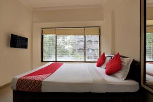 a bedroom with a bed with red pillows and a window at Hotel Lal Sai Residency in Mumbai