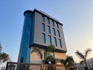 een hoog gebouw met palmbomen ervoor bij The Ecstasy Hotel in Lucknow