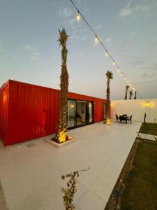 um edifício vermelho com palmeiras em frente em container chalet em Buraydah