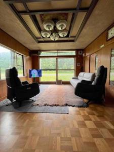 a living room with two chairs and a couch at House surrounded by beautiful nature. in Biei