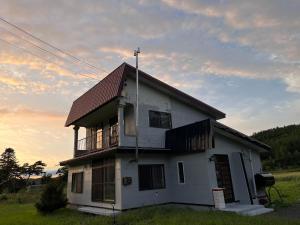 a small white house with a red roof at House surrounded by beautiful nature. in Biei