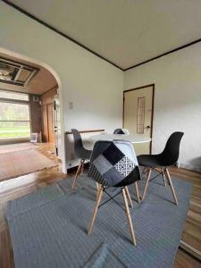 a room with a table and chairs on a rug at House surrounded by beautiful nature. in Biei