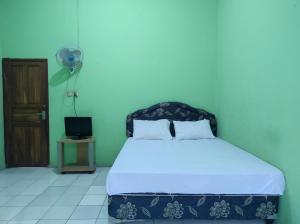 a bedroom with a bed and a fan and a door at OYO 93411 Syariah Hotel Tomborang in Karema