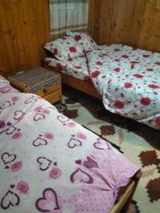 two twin beds in a room with a bedspread with hearts at Cabana Alexe Mărișel in Mărişel