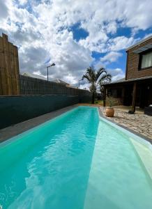 a swimming pool with blue water in front of a house at Villa K'nell - La Possession in La Possession