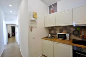 La cuisine est équipée de placards blancs et d'un four micro-ondes. dans l'établissement SECRET GARDEN apartment, à Castellammare di Stabia