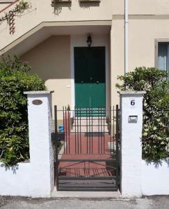 a gate in front of a house with a green door at Casa Rosa Marina di Cecina in Cecina