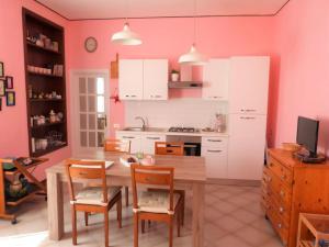 a kitchen with a table and chairs and a kitchen with pink walls at Casa Rosa Marina di Cecina in Cecina