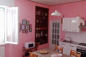 a kitchen with pink walls and a table with a microwave at Casa Rosa Marina di Cecina in Cecina