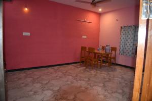 una sala da pranzo con tavolo e parete rossa di Harisri Homestay a Madurai