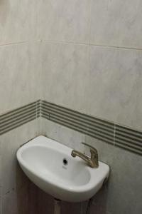 a white sink in a bathroom with a wall at SPOT ON 93553 Juan Kostel in Banyumas