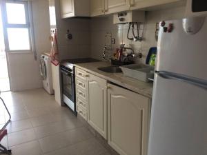 a kitchen with white cabinets and a white refrigerator at Perfect for two in Armação de Pêra