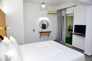 a bedroom with a white bed with a mirror and a tv at Aikaterini Lever Du Soleil in Koskinou