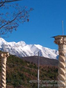 twee zuilen met een met sneeuw bedekte berg op de achtergrond bij Appartamenti Vista Gransasso in LʼAquila