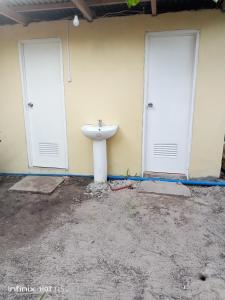 baño con 2 puertas blancas y lavamanos en Akoya Beach Park and Cottages en Locaroc