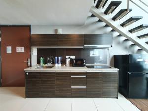 uma cozinha com armários de madeira e um frigorífico preto em Fantastic Seaview Loft 2R2B 9Pax #Maritime em Jelutong