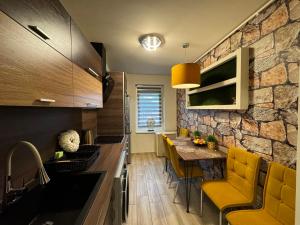 デブレツェンにあるMox Downtown Apartmanの石壁のキッチン(黄色い椅子付)