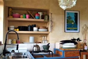 a kitchen with a sink and a shelf with dishes at Farm Stay: Enjoy Fynbos Views & Wood Fired Hot Tub in Hopefield