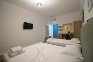 a hotel room with three beds and a television at Ortus Rooms in Sarandë