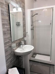 uma casa de banho branca com um lavatório e um chuveiro em Modern Spacious 2BD Penthouse with 2 Terraces - Close to Luqa Airport em Luqa