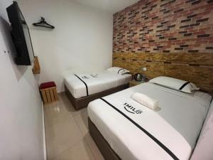 two beds in a room with a brick wall at Seeds Hotel Putrajaya in Putrajaya