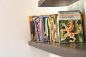 un estante lleno de libros en una pared en Trilocale comodo ai servizi, en Alessandria