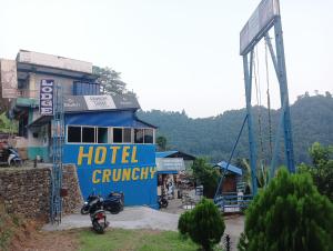 um posto avançado de hotel azul com uma moto estacionada em frente em Hotel crunchy em Deorāli