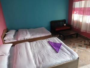 duas camas num quarto com um guardanapo roxo em Hotel crunchy em Deorāli