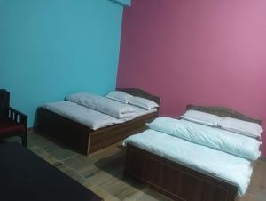 Duas camas num quarto com paredes cor-de-rosa e azul em Hotel crunchy em Deorāli