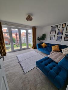 uma sala de estar com um sofá azul e uma grande janela em Glaisdale House em Eston