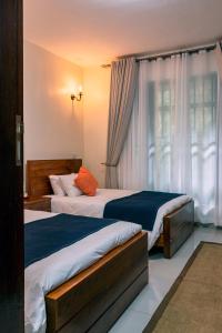 two beds in a hotel room with a window at Sophie's World- 2 Bedroom luxury apartment in Lubowa